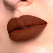 Hypnotic a dark brown liquid lipstick swatched on model.
